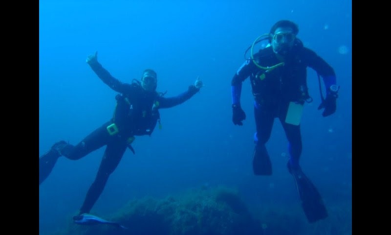 Dos buceadores en aguas azules con pulgar arriba